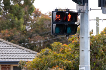 A safety measure:a pedestrian and bicycle traffic signal with a red stop light in a suburban neighborhood.Urban public safety:a combined bike and pedestrian crossing in a residential area in Australia