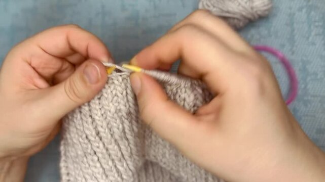knitting process of gray woolen hat with knitting needles. needlework handmade