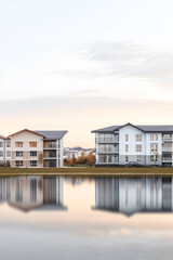 Modern residential buildings reflect in a calm lake at dusk in a serene neighborhood setting