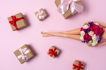 Girl doll with colorful flowers and gift boxes on pink background. Creative minimal holiday or love concept.