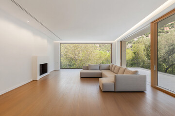 Modern living room with large windows overlooking green landscape in a contemporary home