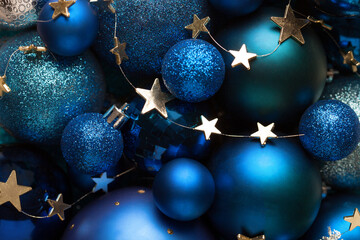 Background with blue Christmas balls and golden stars. Close-up of a pile of blue Christmas balls, different sizes, shades  and textures. Flat lay