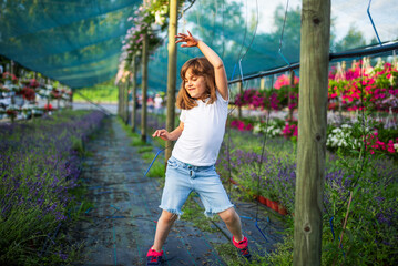 Little girl dancing in a greenhouse surrounded by flowers