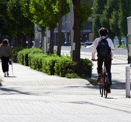 秋の朝の都市の道路で自転車を乗って通勤する人の姿