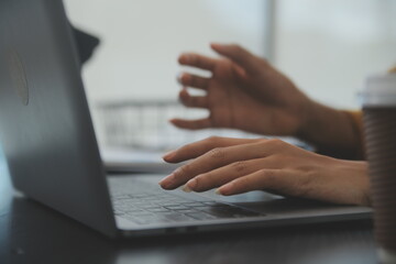 Close up Business woman using calculator and laptop for do math finance on wooden desk, tax, accounting, statistics and analytical research concept