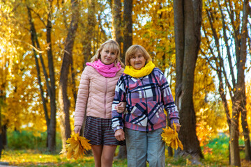 Fototapeta premium Senior woman and granddaughter in autumn park. Selective focus.