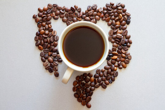 Intestines shape made of coffee beans with cup of coffee, impact of coffee on bowels health, creative concept