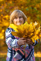 Senior woman in autumn park. Selective focus.