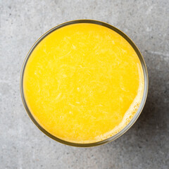 Glass of fresh orange juice on gray stone table