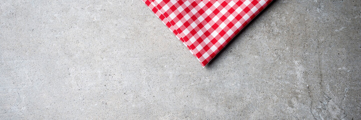 Red folded tablecloth on gray stone table. Top view