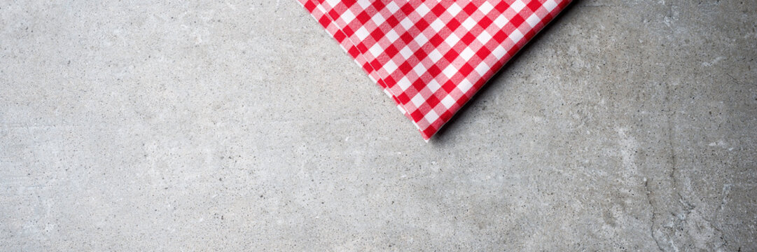 Red folded tablecloth on gray stone table. Top view
