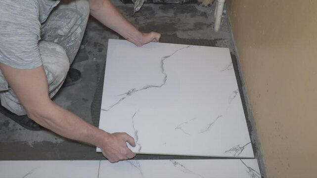 A male worker lays floor tiles