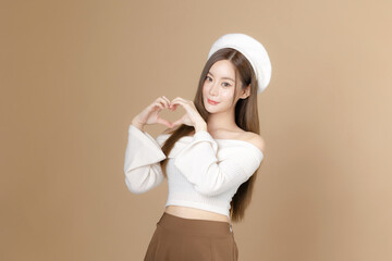 Young Asian beauty woman long hair with beret lovely face and perfect clean skin on isolated beige background. Female model show love sign, Facial treatment, Cosmetology, plastic surgery.