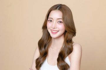 Young Asian beauty woman curly long hair with korean makeup style touch her face and perfect skin on isolated beige background. Facial treatment, Cosmetology, plastic surgery.