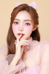 Fototapeta premium Young cute Asian woman in a pink elegant dress, Korean style makeup, moisturized, smooth, perfect skin on a beige background. Facial treatment, Cosmetology, plastic surgery.
