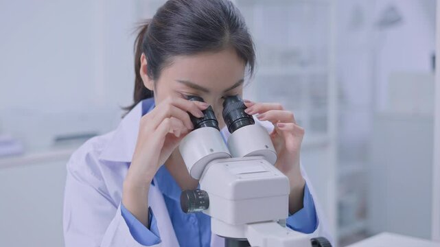 Asian Researcher using a microscope in the clinical lab.Female Researcher working in the clinical laboratory,Medical or scientific researcher or Asian woman doctor looking at professional microscope.
