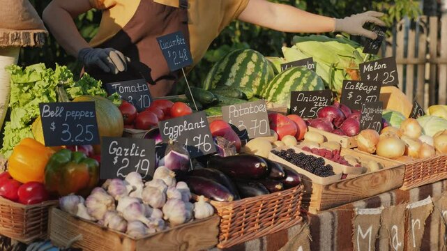 Farmers' market with a variety of fresh vegetables and fruits arranged in baskets and boxes. Price tags with names and prices displayed
