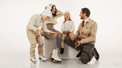 Father kneeling down to help his young daughter lace up her ice skates. Cozy caring moment...