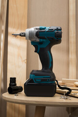 Cordless electric drill and screwdriver on a wooden table.