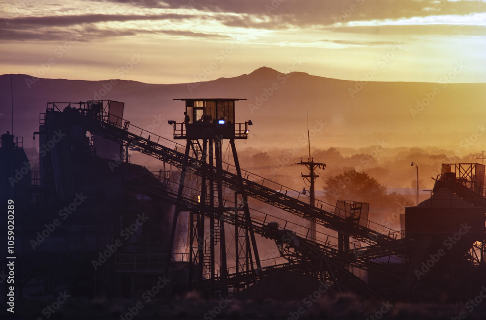 Wall mural industrial site near albuquerque, new mexico. sunset light and mountains. machinery suggesting miner