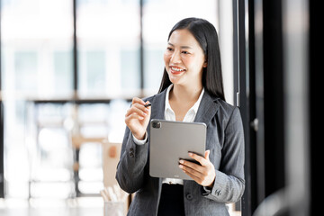 Happy female entrepreneur using tablet while standing in the office and looking up. Copy space.