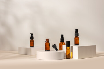 amber glass cosmetic bottles with cream or fluid for skin care on white concrete podium on beige background.