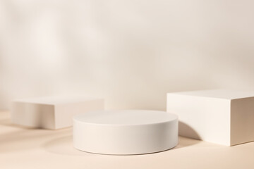 Empty stage with three white podiums on beige background and shadows of tree leaves.