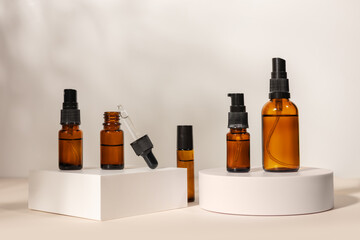 brown glass bottle with a pipette on a podium on a beige background, natural cosmetic concept