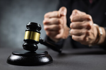 Law theme. Court of law trial in session. Judge's gavel and man in handcuffs in lawyer office or...