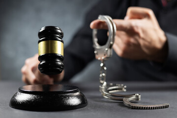 The judge with the gavel announces the verdict and shows the handcuffs,