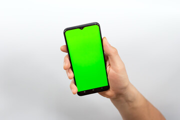Phone screen is green chroma key. Green smartphone screen. Footage for mobile ads. Phone in the hand close up isolated at white background.