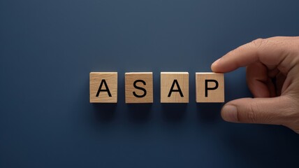 Hand put the ASAP wooden block character on navy background. Urgent and fast respond concept.