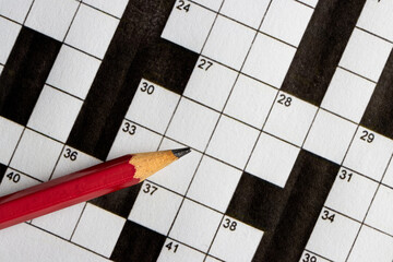 Empty, unfinished crossword puzzle, black and white crossword puzzle with a red pencil. On black background. 