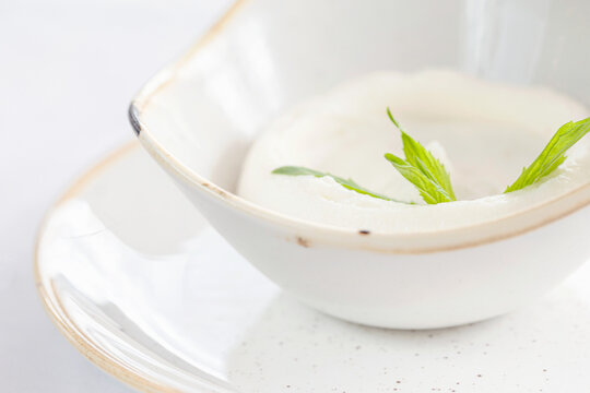 A small bowl of garlic dip topped with herb.