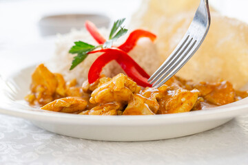Chicken curry served with rice garnished with red pepper and fresh parsley.