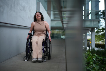 Smiling woman with a disability sitting in a wheelchair doing down the accessibility ramps