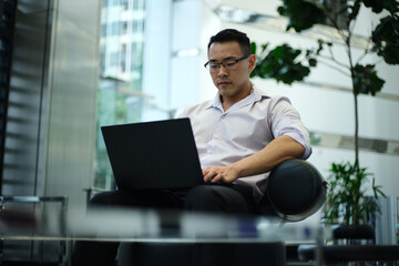 Asian businessman working on laptop in modern workplace