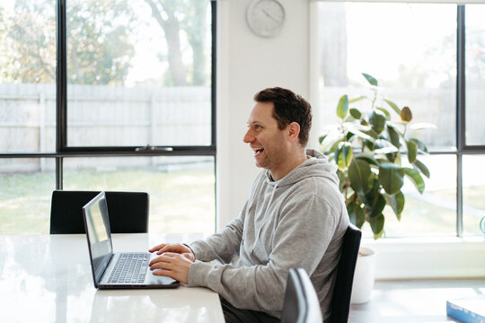 Middle-aged man working on his laptop on the dining table.