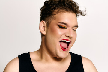 This engaging portrait features a queer individual expressing happiness with creative makeup.