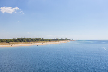 Beautiful sandy beach in Greece, with crystal-clear blue waters and seagulls flying overhead.
