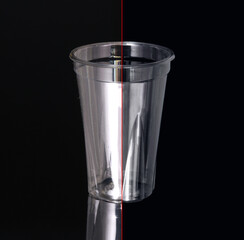 Photos before/after processing. Photo of a disposable clear plastic cup on a dark background. Subject photography.