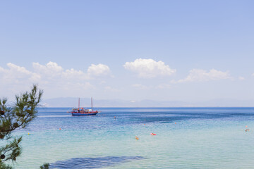 Obraz premium Beautiful Mediterranean coastal scene featuring a colorful sailboat floating on crystal-clear waters.