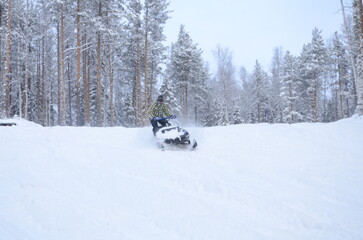 A guy rides a snowmobile through the forest