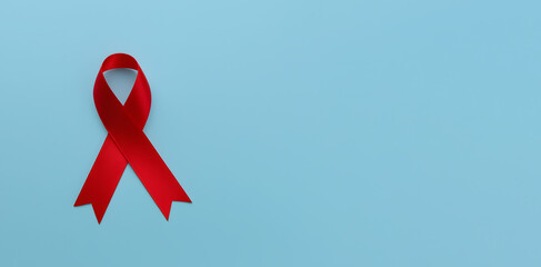 Red awareness and support ribbon isolated on blue background. World hiv aids day concept, 1 december, awareness banner with copy space