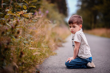 Young Boy Sitting on Pathway, Lost in Thought