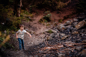 Obraz premium Young Boy Standing on Rocky Terrain in Forest, Observing Surroundings