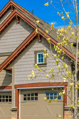 Top of grey stucco luxury house with shingle roof, red and yellow trees and nice windows in Summer in Vancouver, Canada, North America. Day time on June 2024.