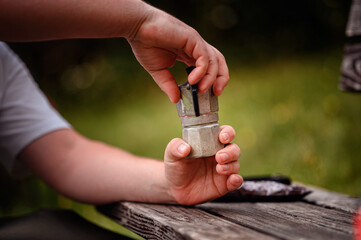 Fototapeta premium Hands Preparing Moka Pot for Coffee Outdoors