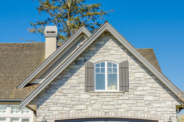 Obraz premium Top of grey stucco luxury house with shingle roof, red and yellow trees and nice windows in Summer in Vancouver, Canada, North America. Day time on June 2024.