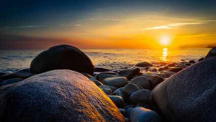 Granite rocks on the ocean shore against the backdrop of sunset.